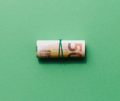 elevated-view-rolled-up-fifty-euro-note-green-background-min
