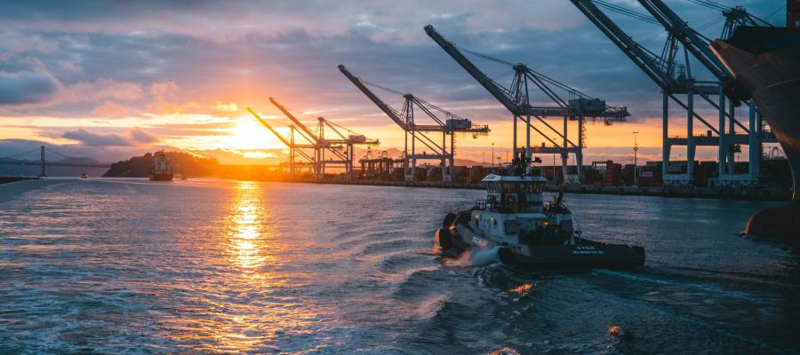 a panoramic shot of oil rigs at sea with a beautiful sunset in the background, under cloudy sky